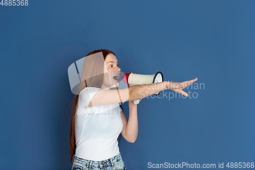 Image of Caucasian young girl\'s portrait isolated on blue studio background. Beautiful female model. Concept of human emotions, facial expression, sales, ad, youth culture.