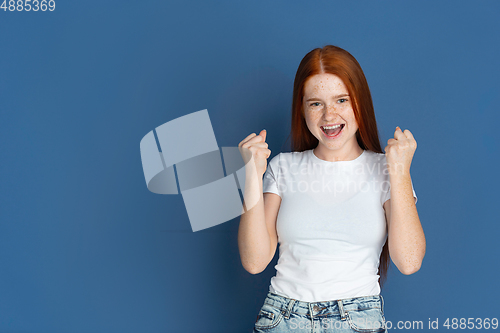 Image of Caucasian young girl\'s portrait isolated on blue studio background. Beautiful female model. Concept of human emotions, facial expression, sales, ad, youth culture.