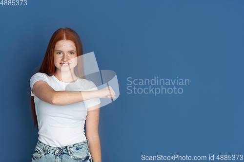 Image of Caucasian young girl\'s portrait isolated on blue studio background. Beautiful female model. Concept of human emotions, facial expression, sales, ad, youth culture.