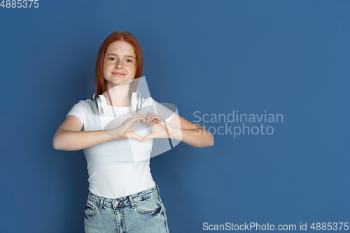 Image of Caucasian young girl\'s portrait isolated on blue studio background. Beautiful female model. Concept of human emotions, facial expression, sales, ad, youth culture.