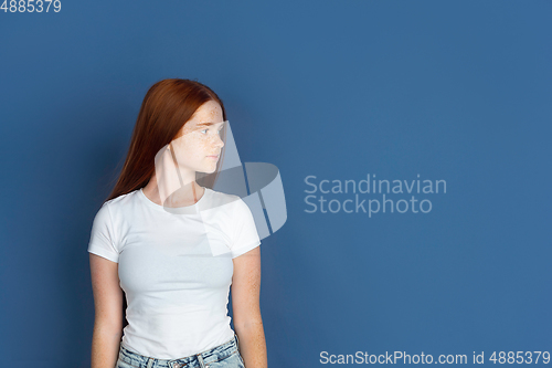 Image of Caucasian young girl\'s portrait isolated on blue studio background. Beautiful female model. Concept of human emotions, facial expression, sales, ad, youth culture.