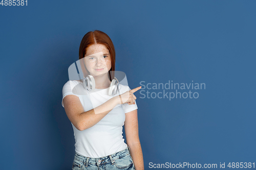 Image of Caucasian young girl\'s portrait isolated on blue studio background. Beautiful female model. Concept of human emotions, facial expression, sales, ad, youth culture.