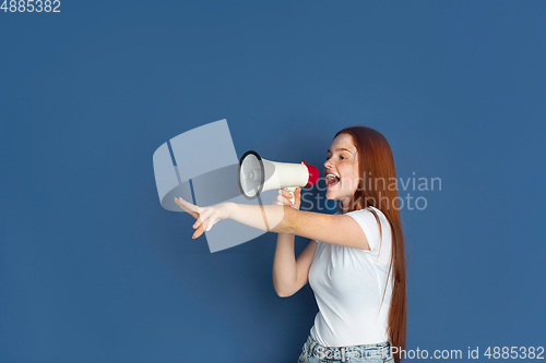 Image of Caucasian young girl\'s portrait isolated on blue studio background. Beautiful female model. Concept of human emotions, facial expression, sales, ad, youth culture.