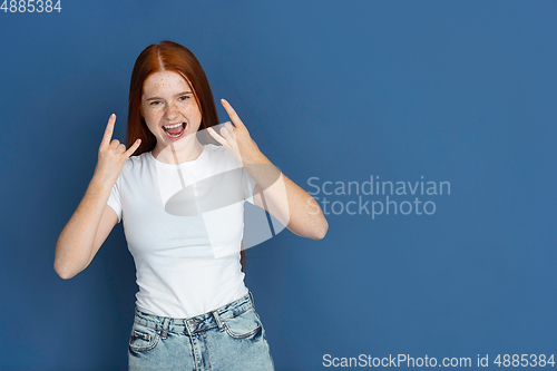 Image of Caucasian young girl\'s portrait isolated on blue studio background. Beautiful female model. Concept of human emotions, facial expression, sales, ad, youth culture.