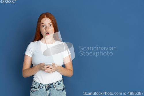 Image of Caucasian young girl\'s portrait isolated on blue studio background. Beautiful female model. Concept of human emotions, facial expression, sales, ad, youth culture.