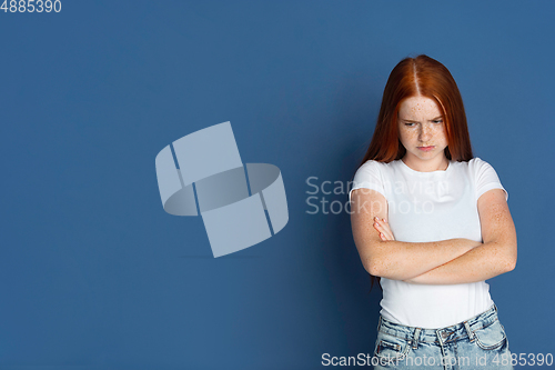 Image of Caucasian young girl\'s portrait isolated on blue studio background. Beautiful female model. Concept of human emotions, facial expression, sales, ad, youth culture.