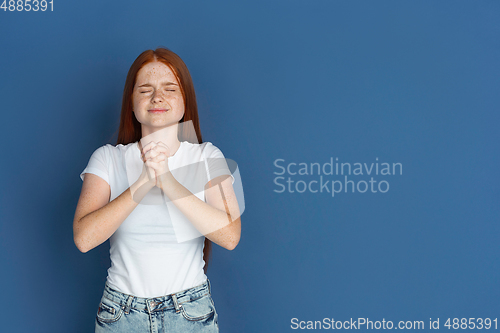 Image of Caucasian young girl\'s portrait isolated on blue studio background. Beautiful female model. Concept of human emotions, facial expression, sales, ad, youth culture.