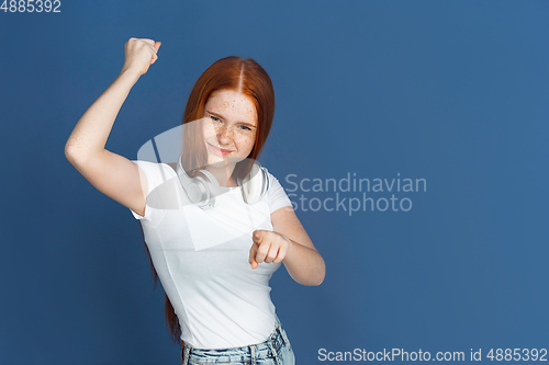 Image of Caucasian young girl\'s portrait isolated on blue studio background. Beautiful female model. Concept of human emotions, facial expression, sales, ad, youth culture.