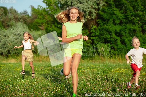 Image of Kids, children running on meadow in summer\'s sunlight