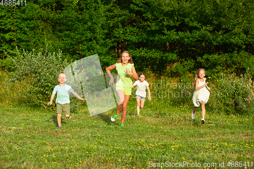 Image of Kids, children running on meadow in summer\'s sunlight