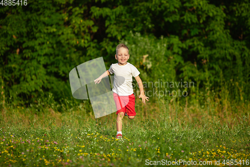 Image of Kid, little boy running on meadow in summer\'s sunlight