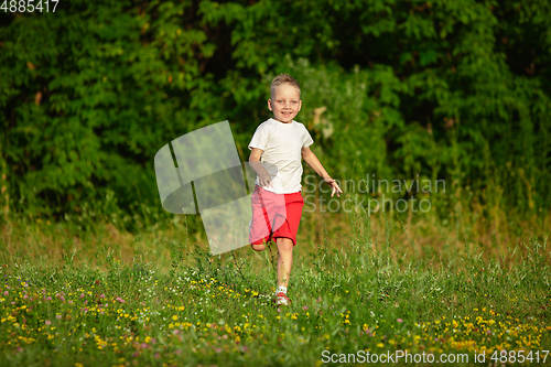 Image of Kid, little boy running on meadow in summer\'s sunlight