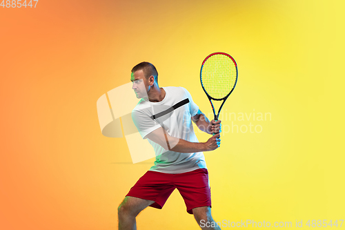 Image of Caucasian male professional sportsman playing tennis on studio background in neon light