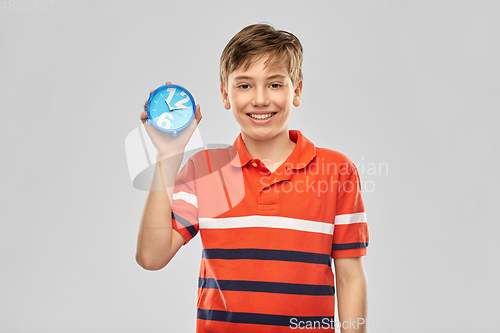 Image of portrait of happy smiling boy with alarm clock