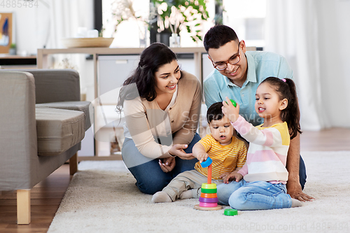 Image of happy family playing with pyramid toy at home