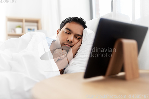 Image of indian man sleeping in bed and tablet pc at home