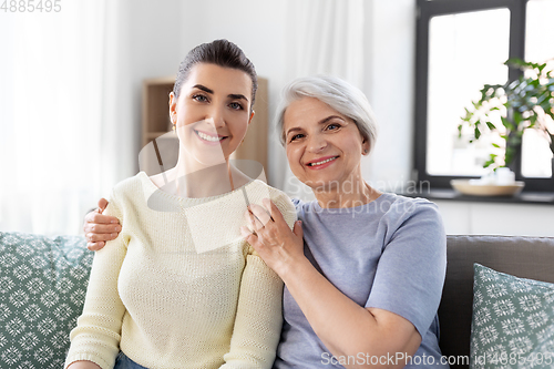Image of senior mother with adult daughter hugging at home