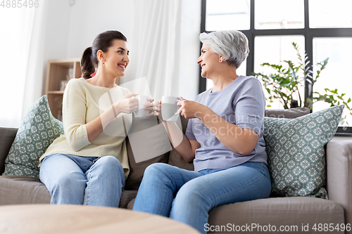 Image of senior mother and adult daughter drinking coffee