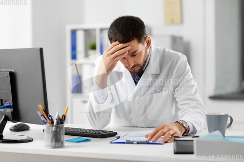 Image of stressed male doctor with clipboard at hospital