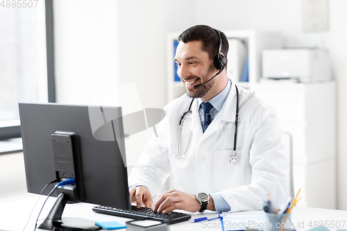 Image of happy doctor with computer and headset at hospital