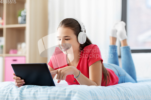 Image of girl in headphones listening to music on tablet pc