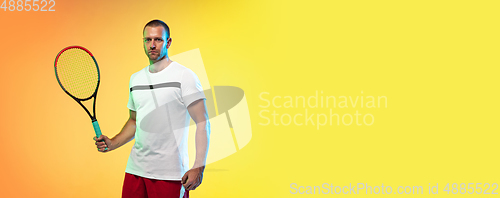 Image of Caucasian male professional sportsman playing tennis on studio background in neon light