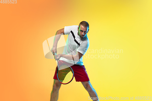 Image of Caucasian male professional sportsman playing tennis on studio background in neon light