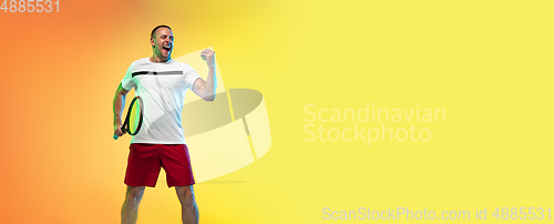 Image of Caucasian male professional sportsman playing tennis on studio background in neon light