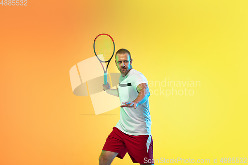 Image of Caucasian male professional sportsman playing tennis on studio background in neon light