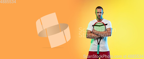 Image of Caucasian male professional sportsman playing tennis on studio background in neon light