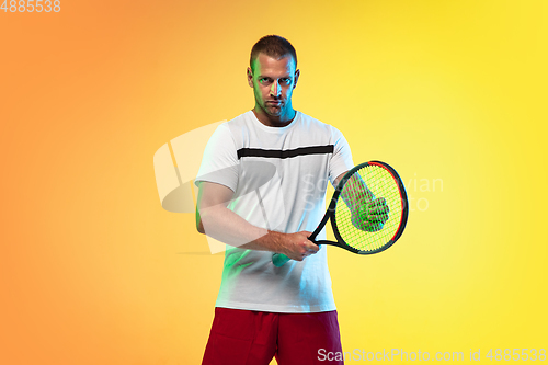 Image of Caucasian male professional sportsman playing tennis on studio background in neon light