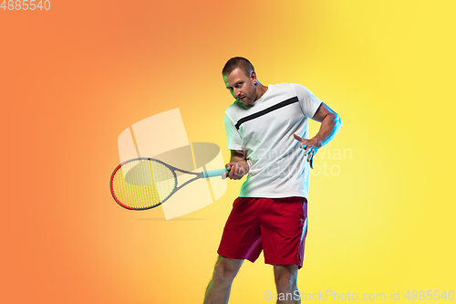 Image of Caucasian male professional sportsman playing tennis on studio background in neon light