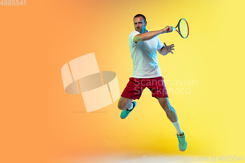 Image of Caucasian male professional sportsman playing tennis on studio background in neon light