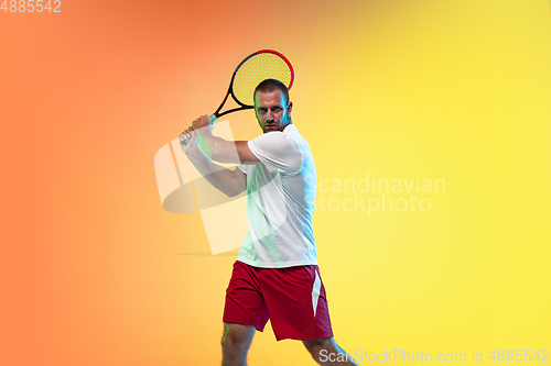 Image of Caucasian male professional sportsman playing tennis on studio background in neon light