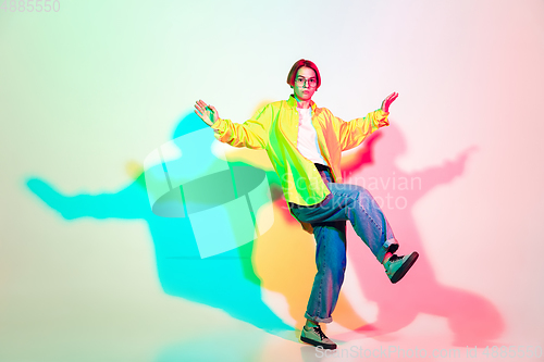 Image of Young beautiful woman dancing hip-hop, street style isolated on studio background in neon light