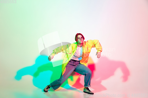 Image of Young beautiful woman dancing hip-hop, street style isolated on studio background in neon light