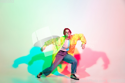 Image of Young beautiful woman dancing hip-hop, street style isolated on studio background in neon light