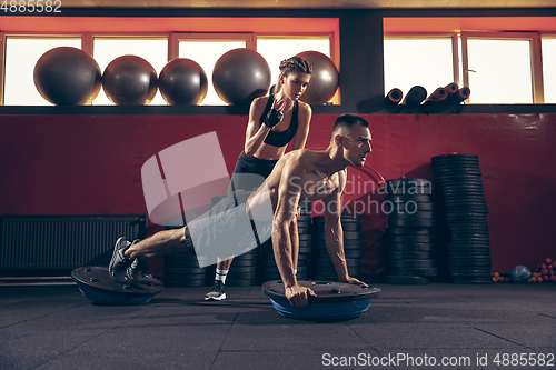 Image of Beautiful young sporty couple training, workout in gym together