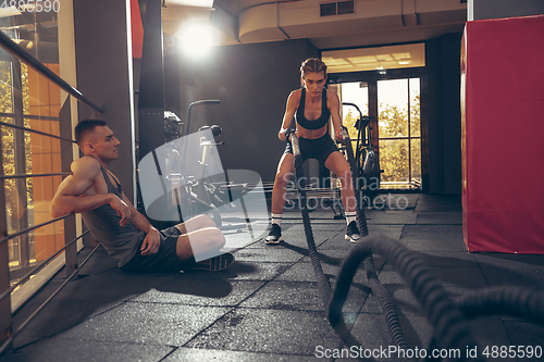 Image of Beautiful young sporty couple training, workout in gym together