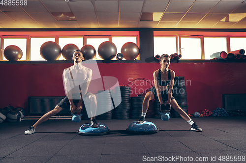 Image of Beautiful young sporty couple training, workout in gym together