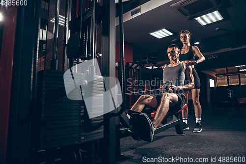 Image of Beautiful young sporty couple training, workout in gym together