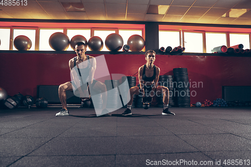 Image of Beautiful young sporty couple training, workout in gym together