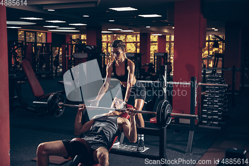 Image of Beautiful young sporty couple training, workout in gym together