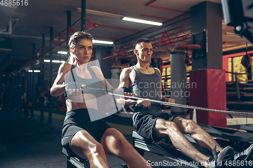 Image of Beautiful young sporty couple training, workout in gym together