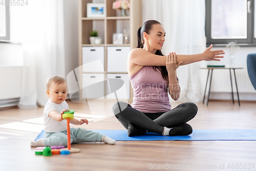 Image of happy mother with little baby exercising at home