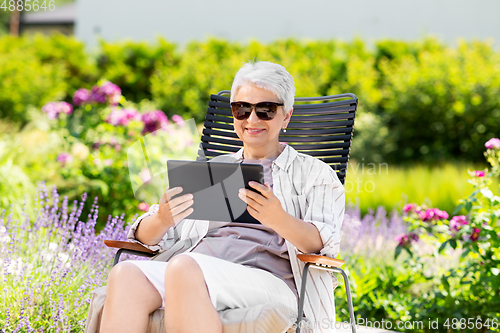 Image of happy senior woman with tablet pc at summer garden