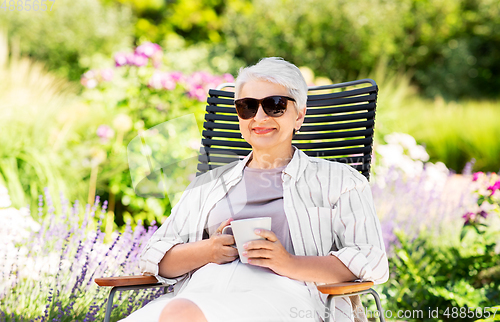 Image of happy senior woman drinking coffee at garden