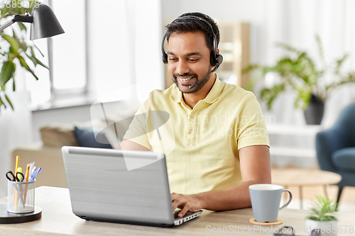 Image of indian man with headset and laptop working at home