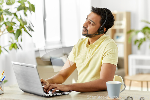 Image of indian man with headset and laptop working at home
