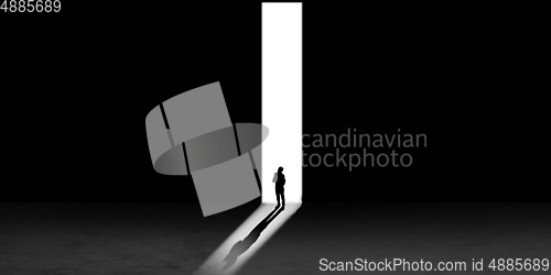 Image of Silhouette of man walking in the night toward the light, view from above